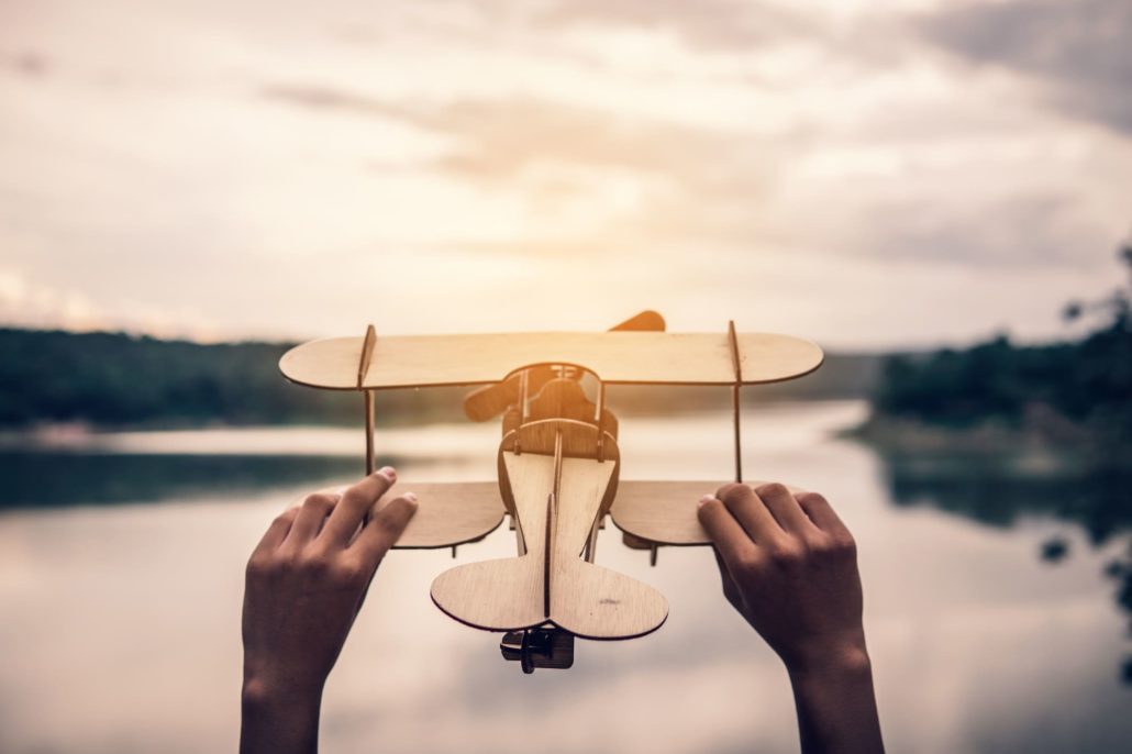 Manos sujetando un avión de madera en la naturaleza