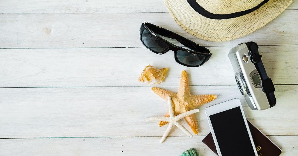 Claves para buscar trabajo en verano, mesa con objetos de verano, gafas de sol, sombrero y estrellas de mar.