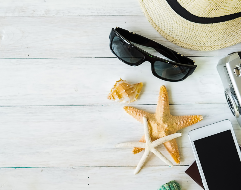 Claves para buscar trabajo en verano, mesa con objetos de verano, gafas de sol, sombrero y estrellas de mar.